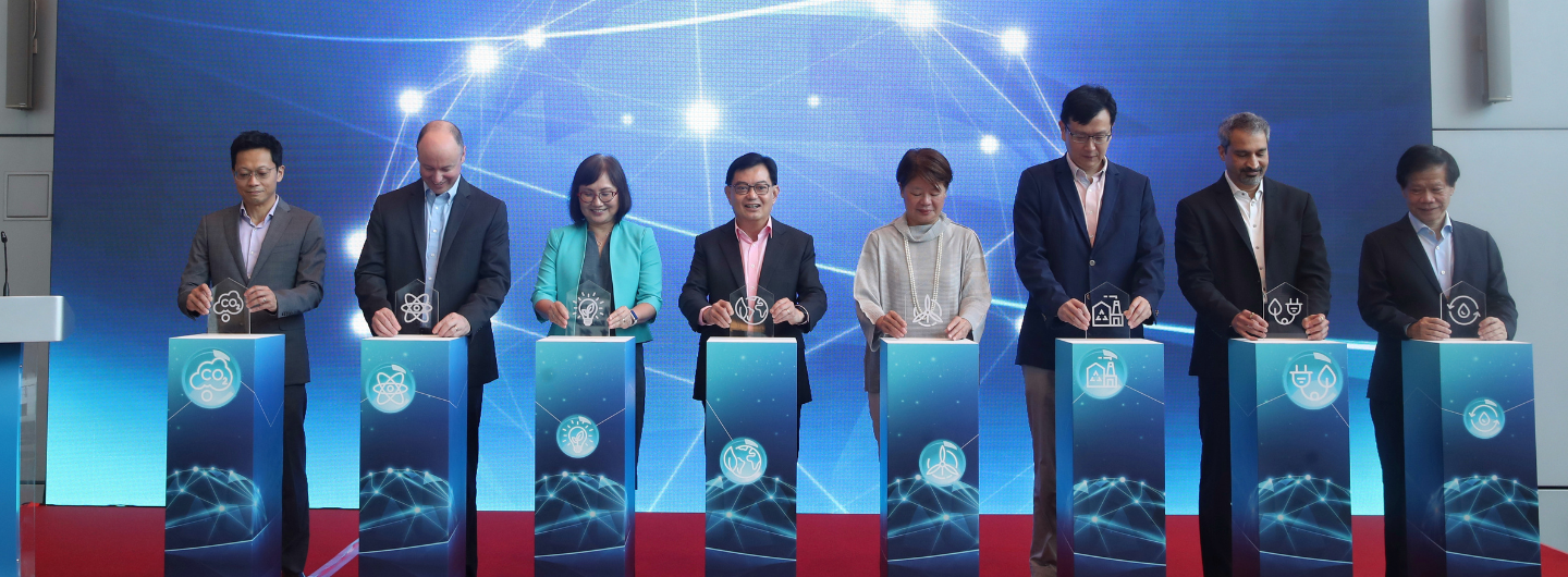 Eight people stand behind pedestals holding awards against a blue digital background.